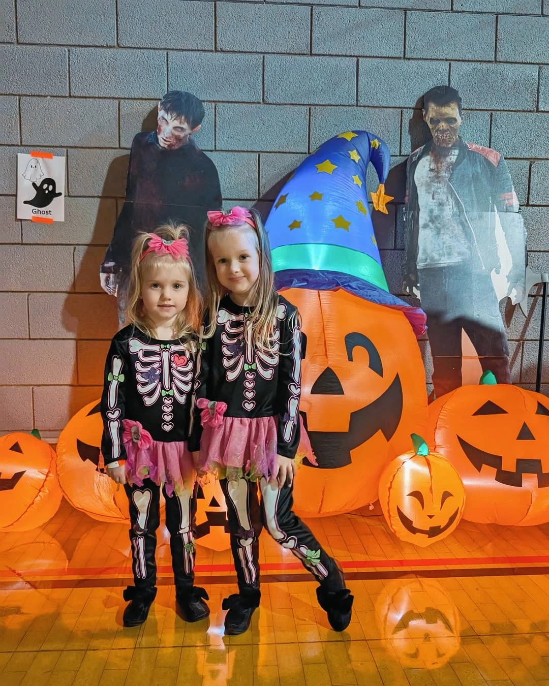 Two girls in matching skeleton costumes with black tutus pink belts and bows