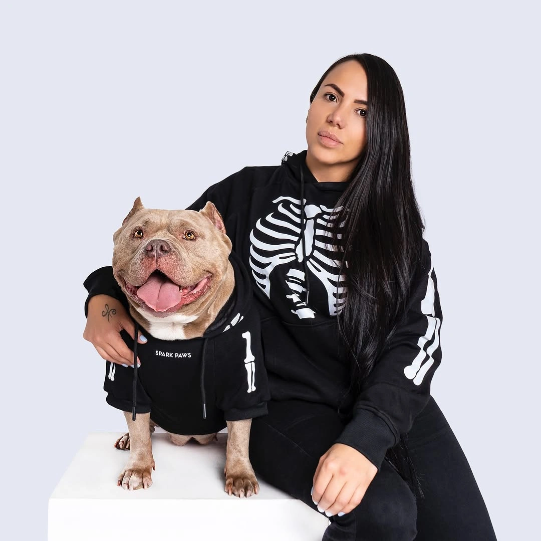 Girl in black skeleton sweatshirt and joggers with matching dog outfit
