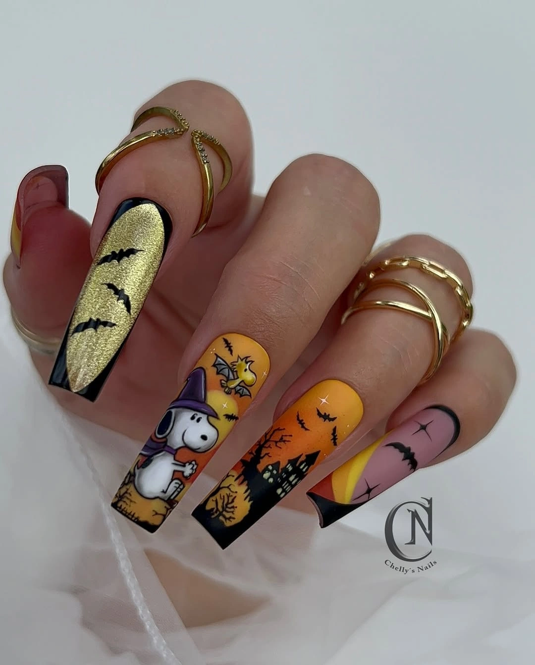 Long pointed yellow orange nails with black and white cartoon motifs