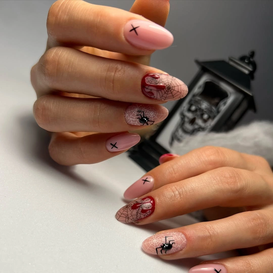 Long almond nude nails with deep red webwork and dark accents