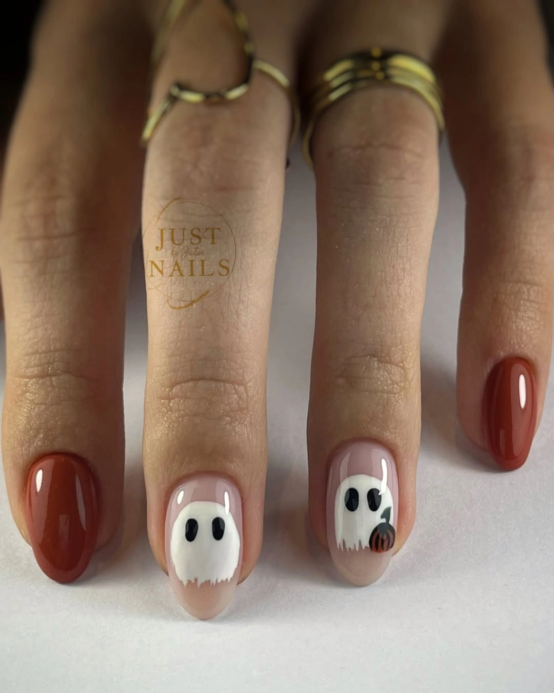 Short rounded red nude nails with simple white ghost faces