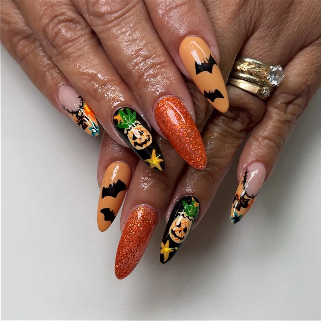 Long almond nails with orange glitter bats and pumpkin art