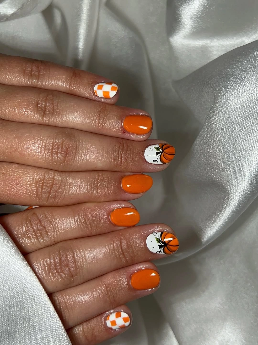 Short orange nails with checkerboard accents ghost and tiny pumpkins