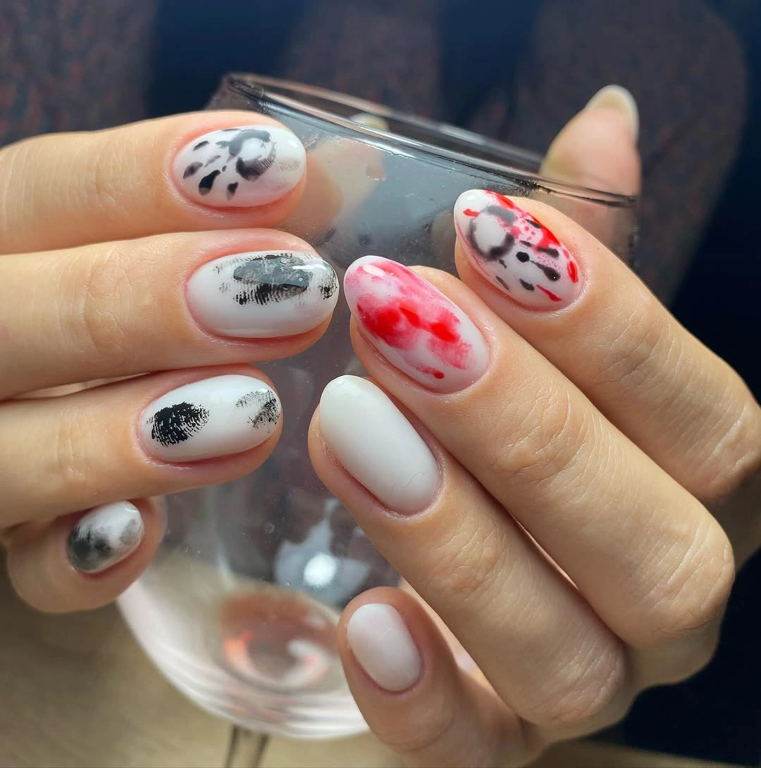 Short rounded white nails with black gray and red splatter motifs