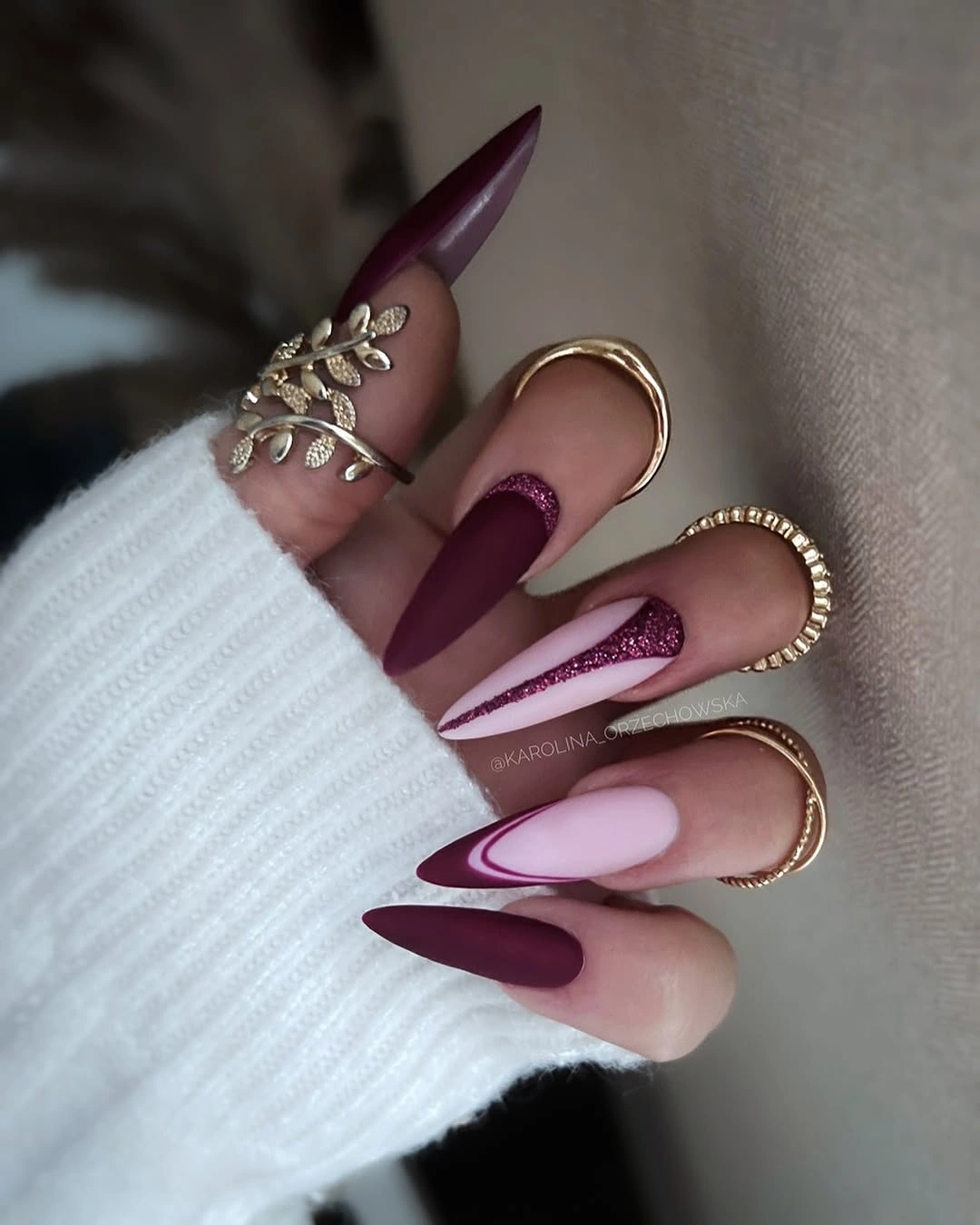 Matte burgundy stiletto nails with pale pink chevrons and thin glitter lines