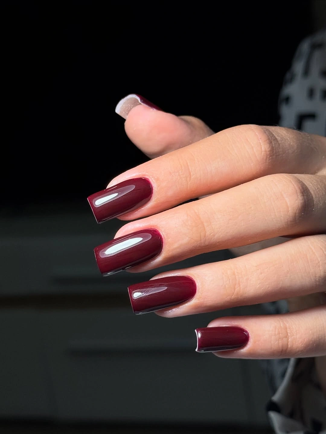 Long tapered square nails in a dark blackened plum-burgundy glossy shade