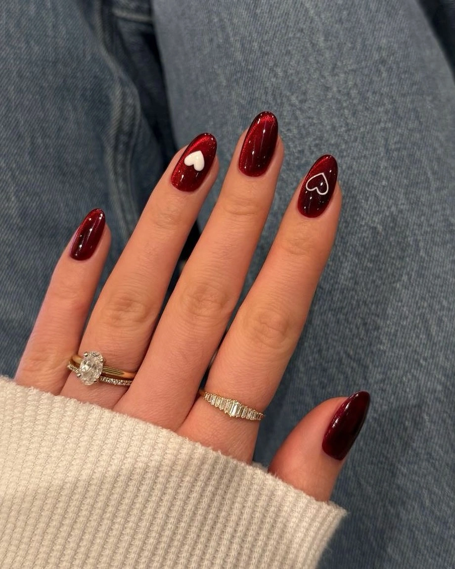 Long glossy burgundy almond nails with one small white heart accent