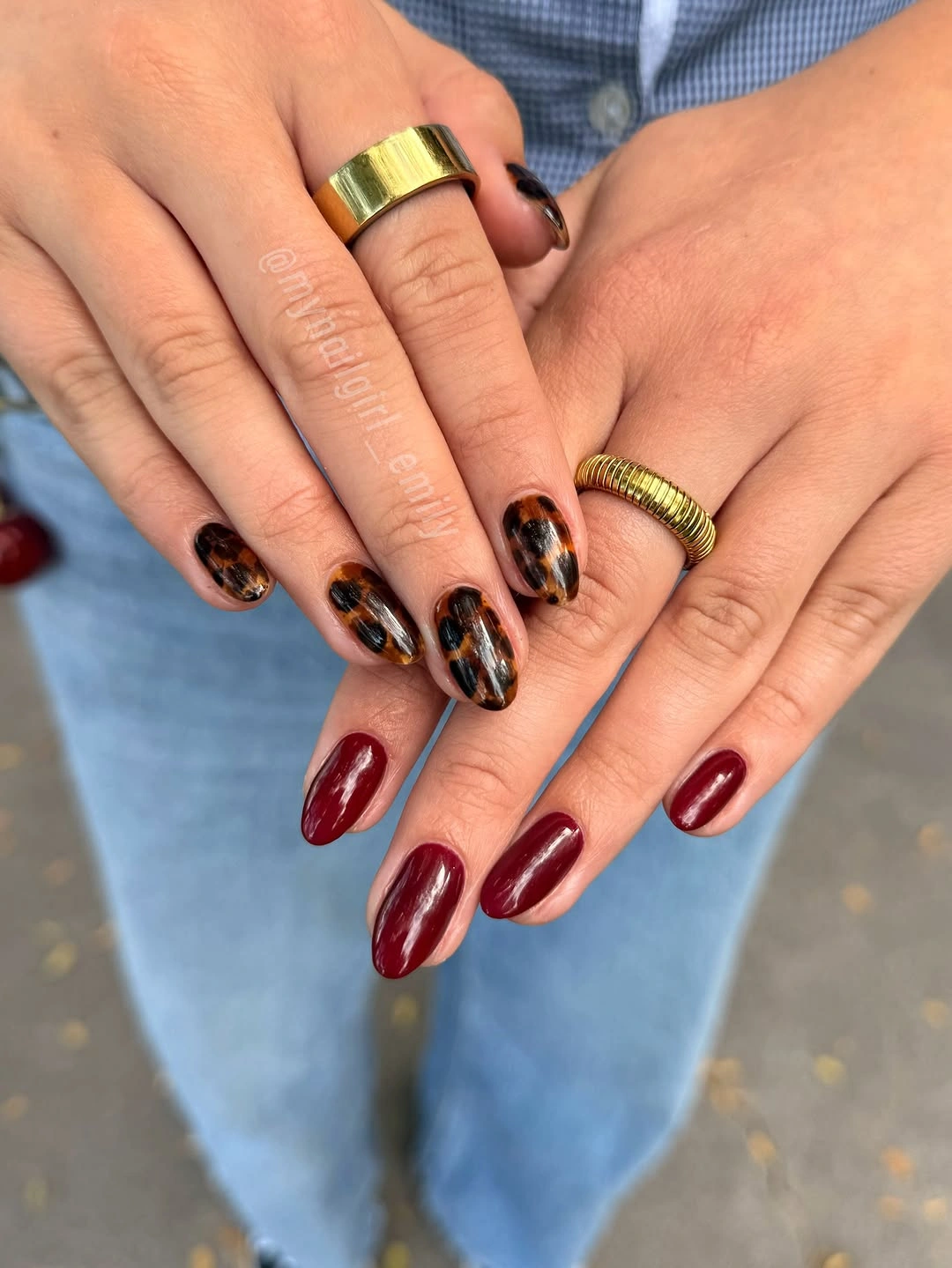 Burgundy almond nails with black and gold abstract patterned accent nails