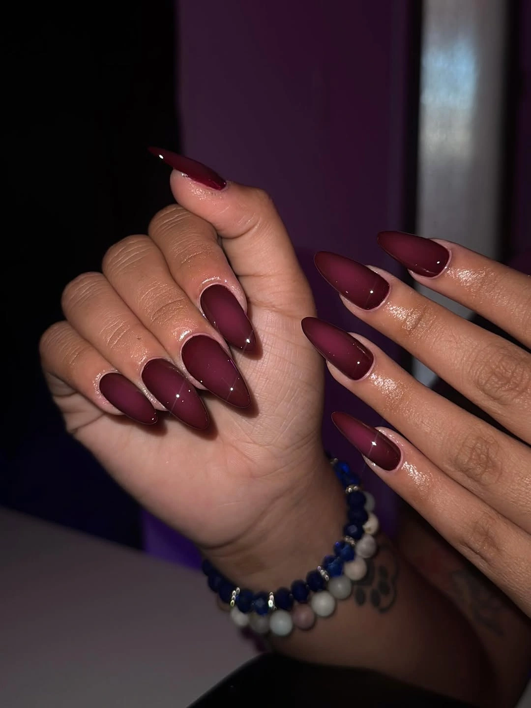 Long matte burgundy stiletto nails in an even non-reflective finish
