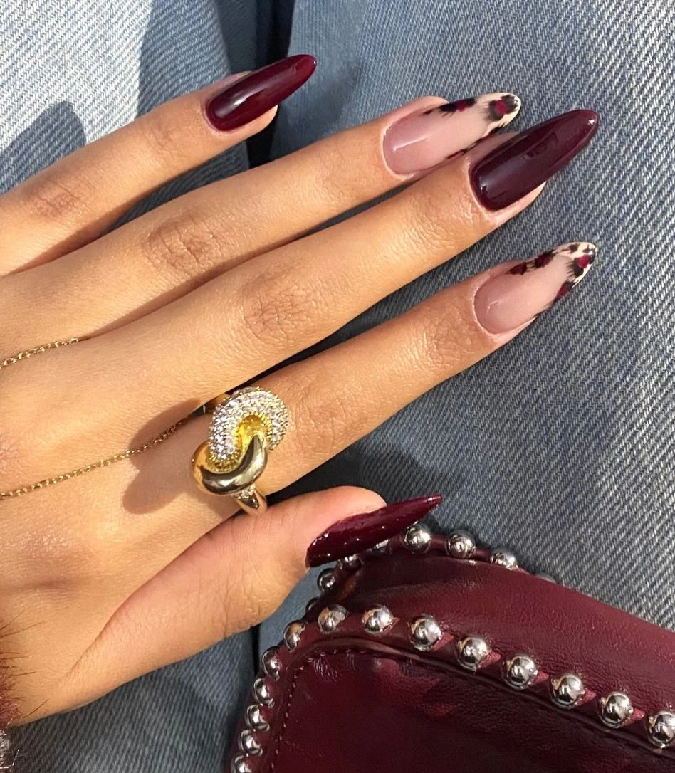 Burgundy pointed nails with nude pink accents and black spotted details