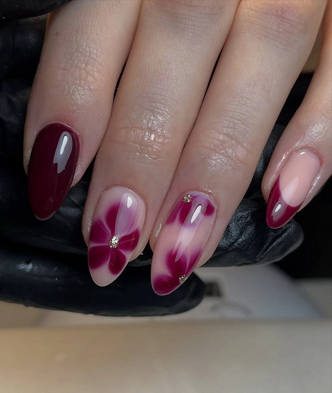 Medium oval nails with soft burgundy petal-like accents on pale bases