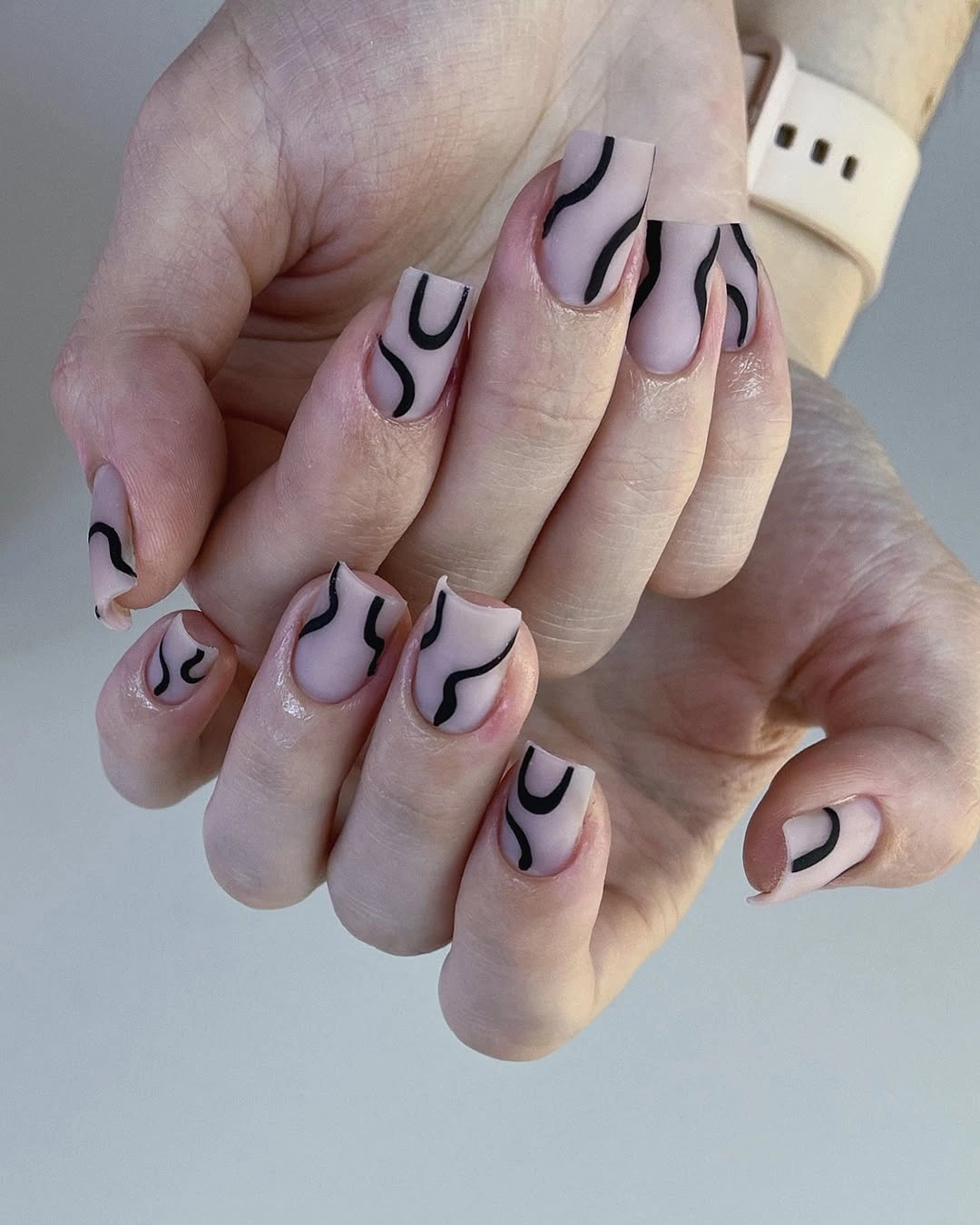 Pale pink square nails with bold black abstract curved linework