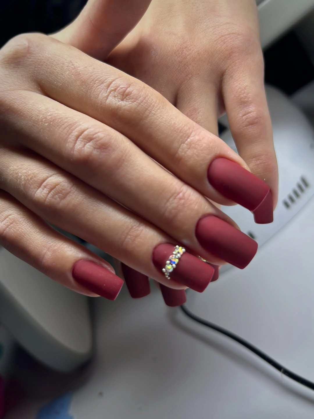 Long matte burgundy square nails with a small curved crystal accent