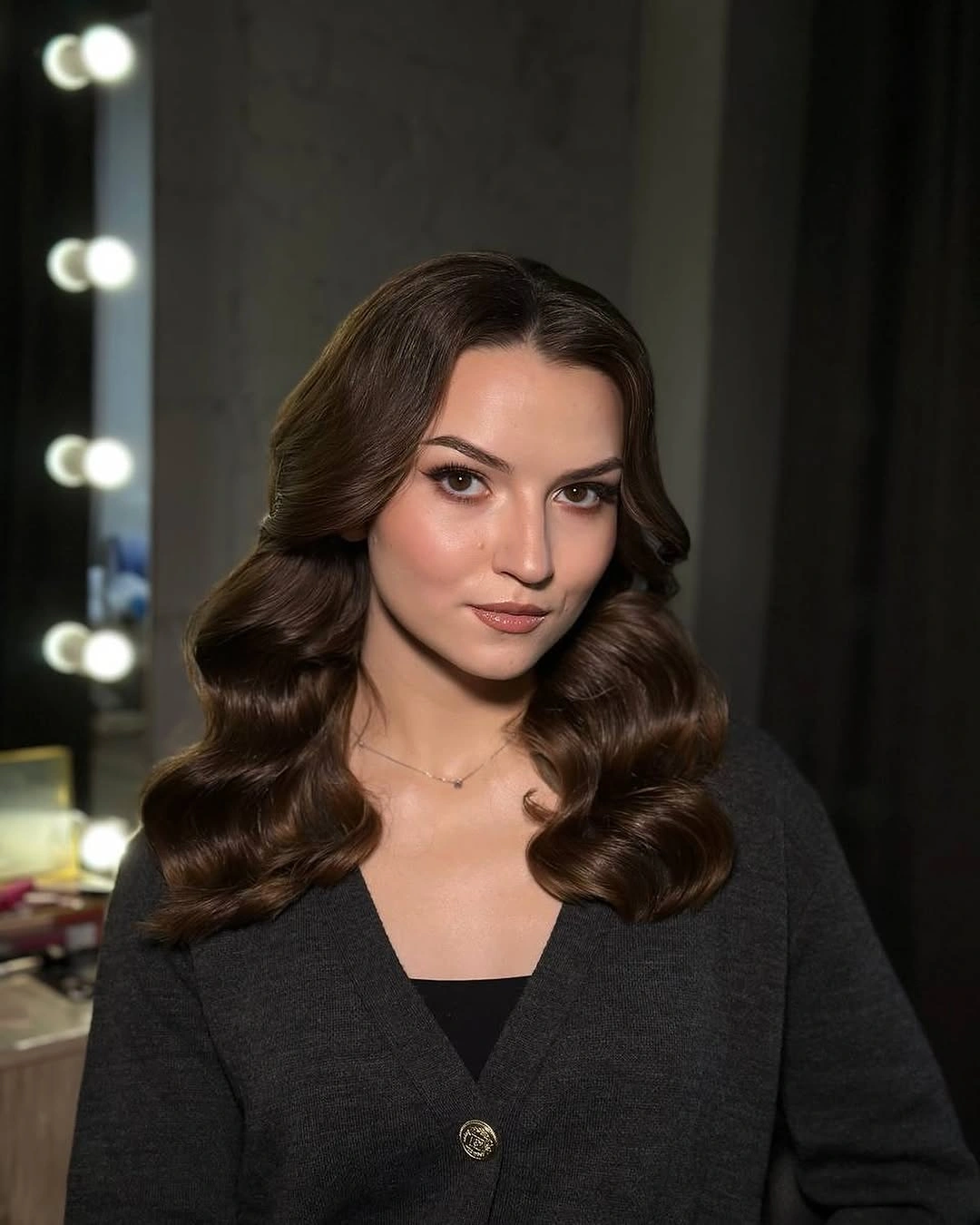 Medium brunette center-parted hair in structured shoulder-length waves