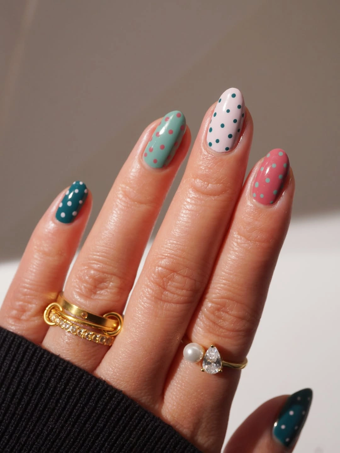 Muted teal mint blush and deep green almond nails with small contrasting dots