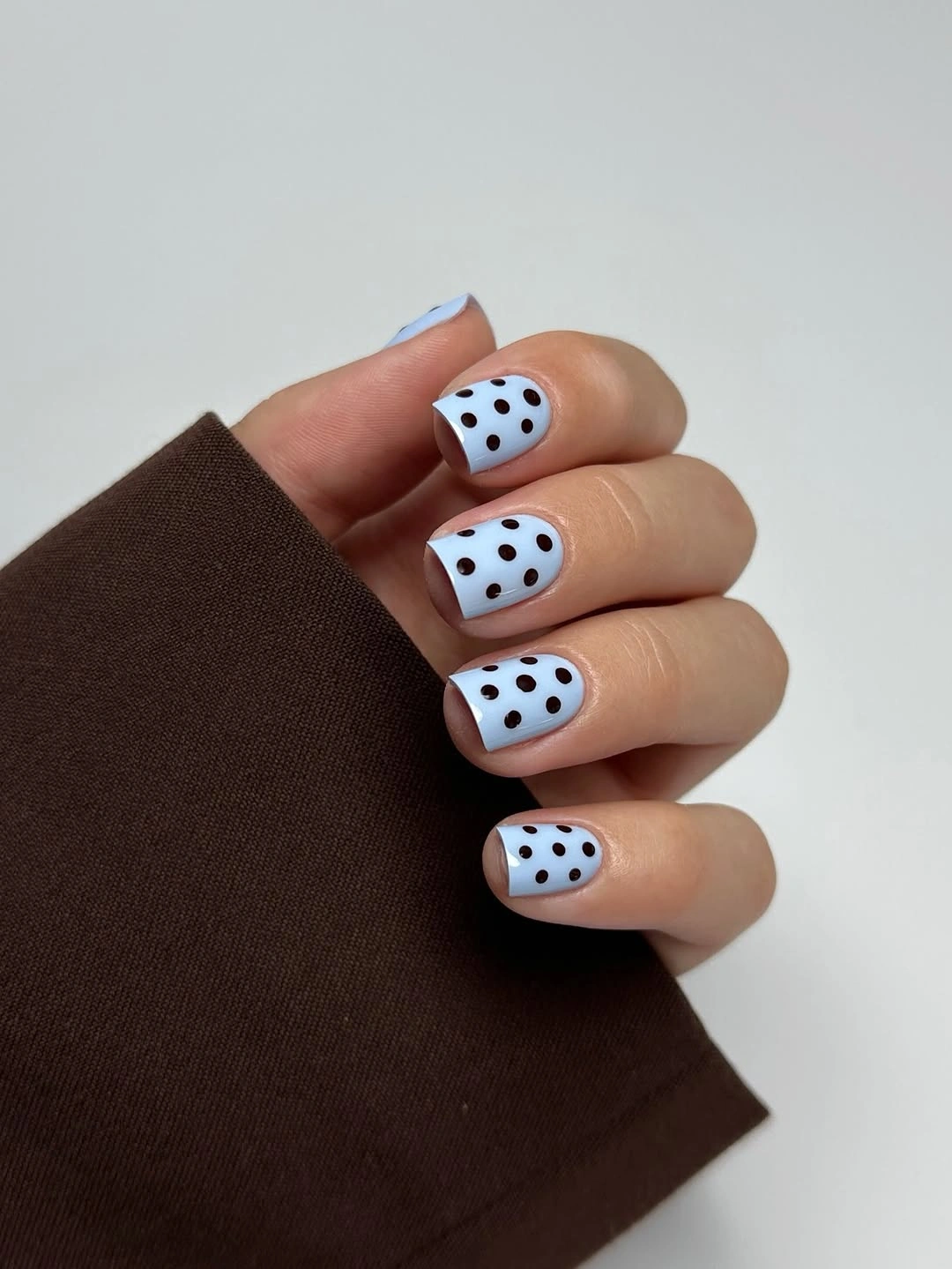 Short pale blue square nails with bold black polka dots