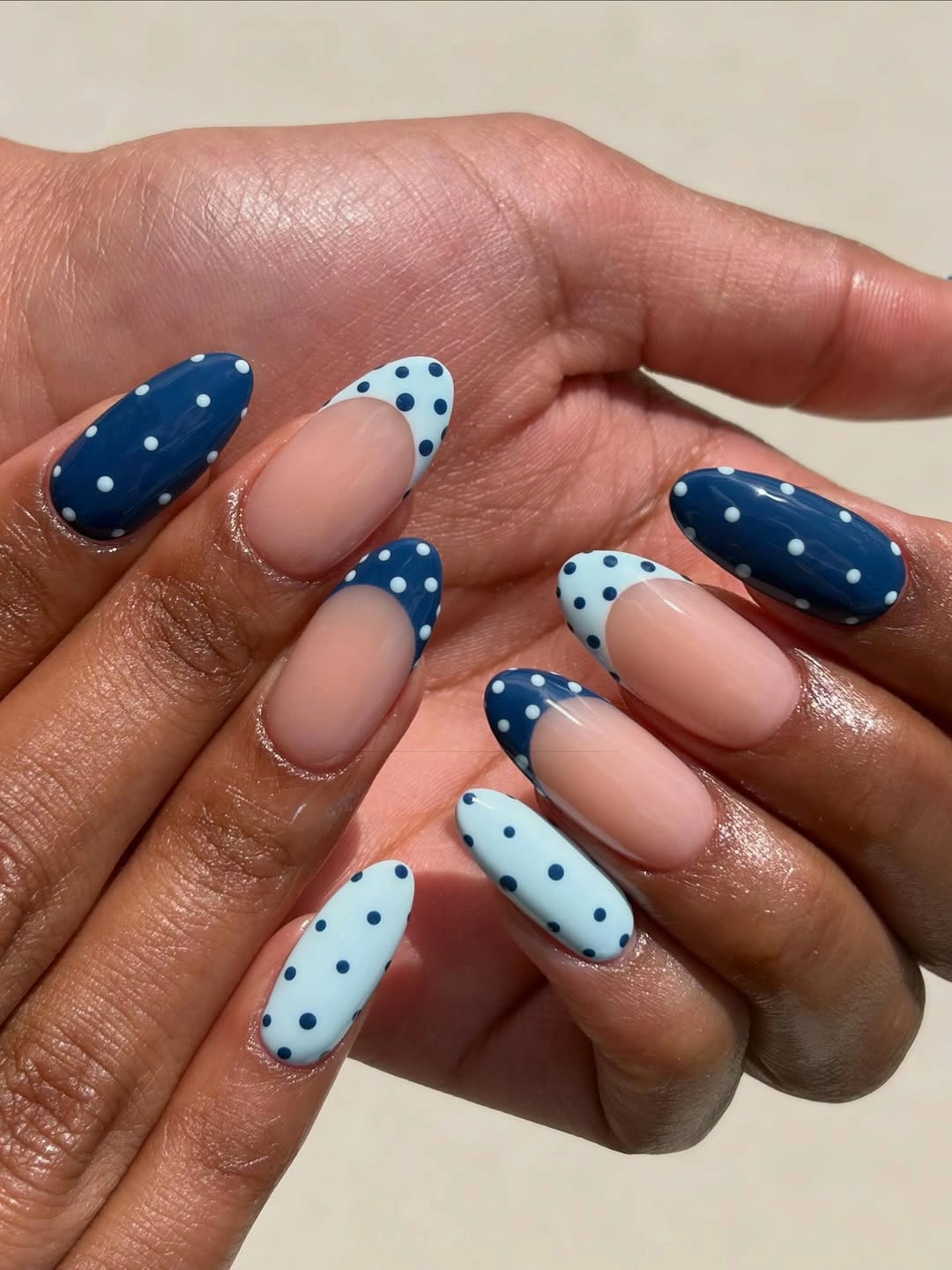 Navy pale blue and blush oval nails with contrasting white dot patterns