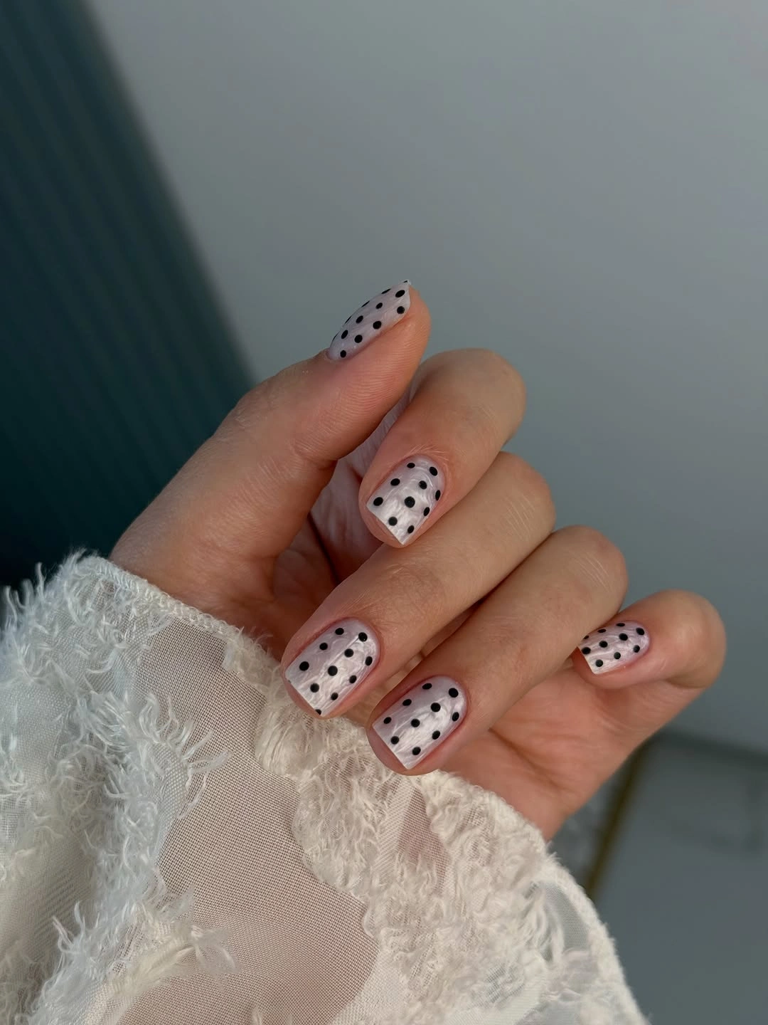 Pale pink square nails with evenly spaced black polka dots