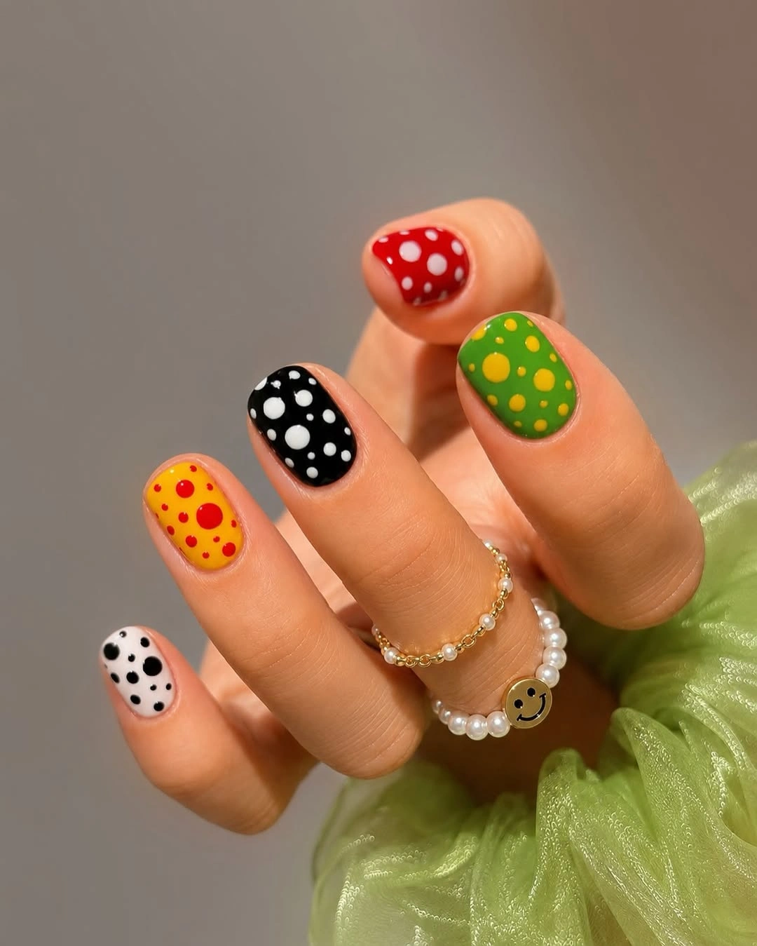 Short multicolor nails in red yellow green black and white with contrasting dots