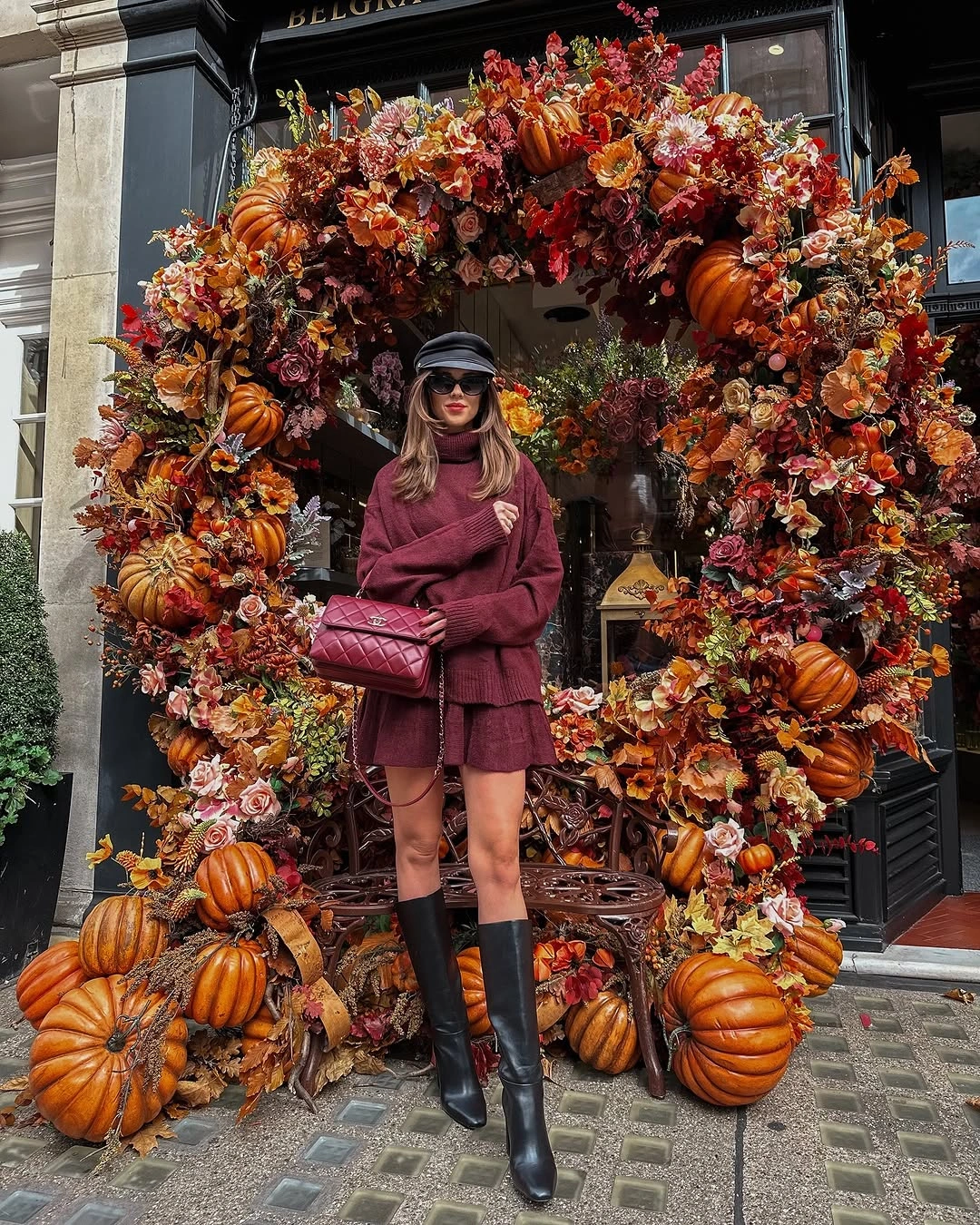 Burgundy jacket and skirt with cap tall boots and quilted bag