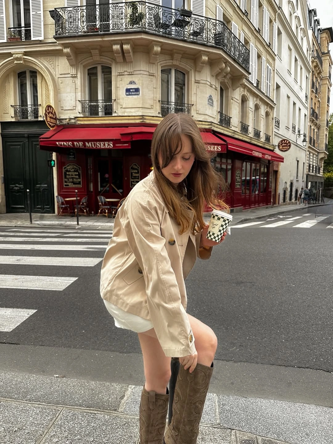 Beige cropped jacket with tall brown boots and pale clutch