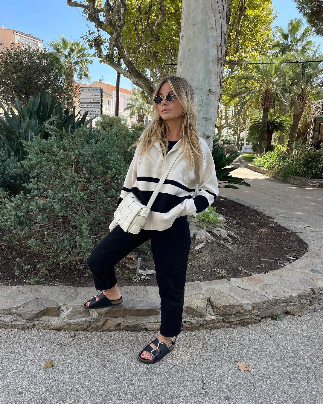 Cream striped knit with black trousers and white shoulder bag