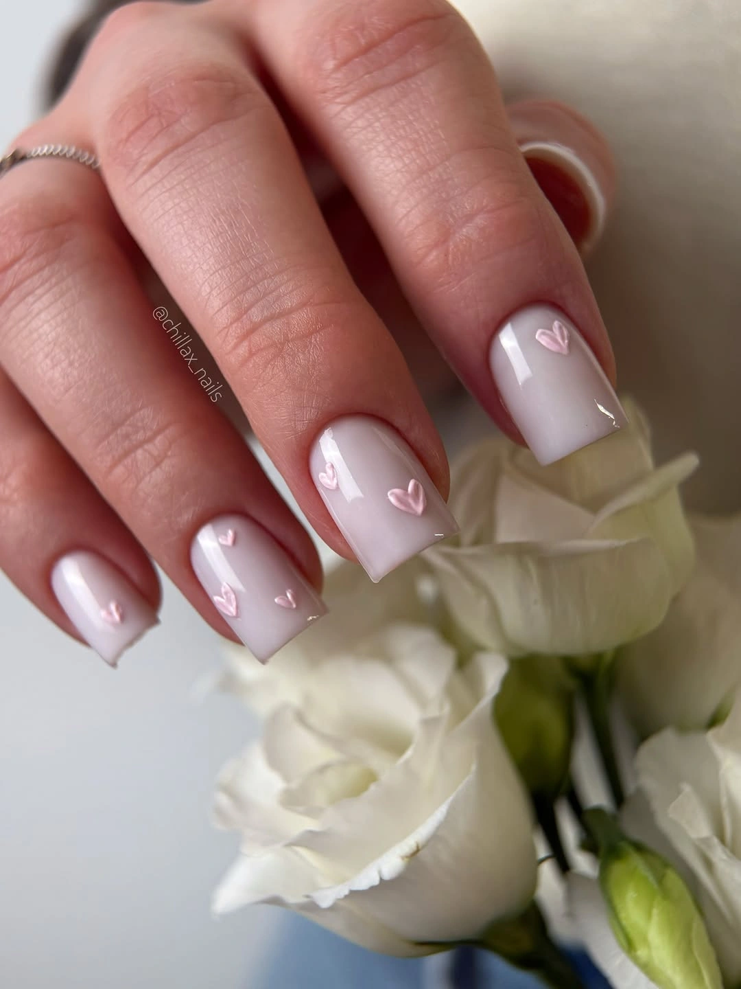 Milky pink square nails with small white heart accents