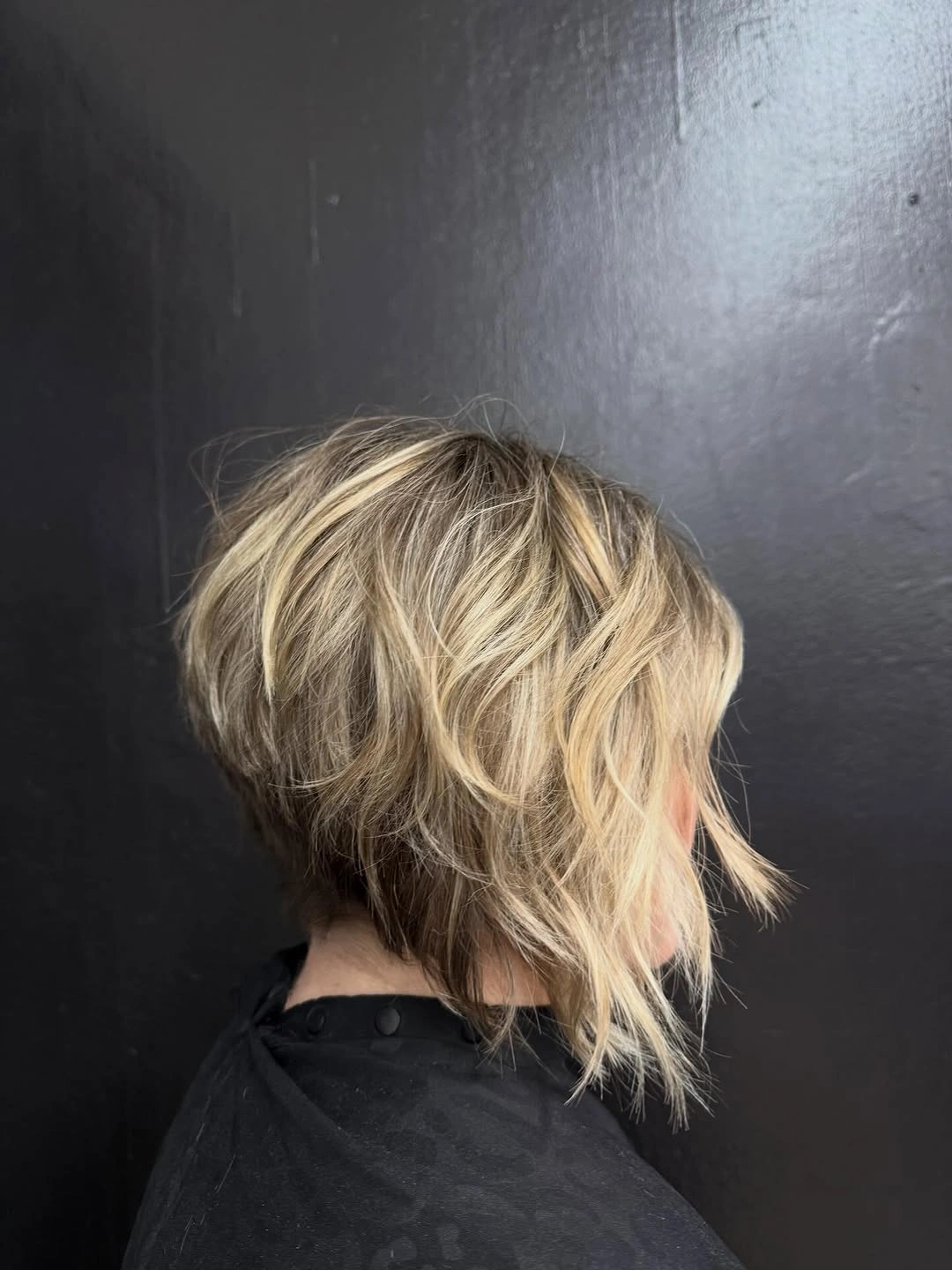 Short wavy blonde bob with darker interior and piecey ends