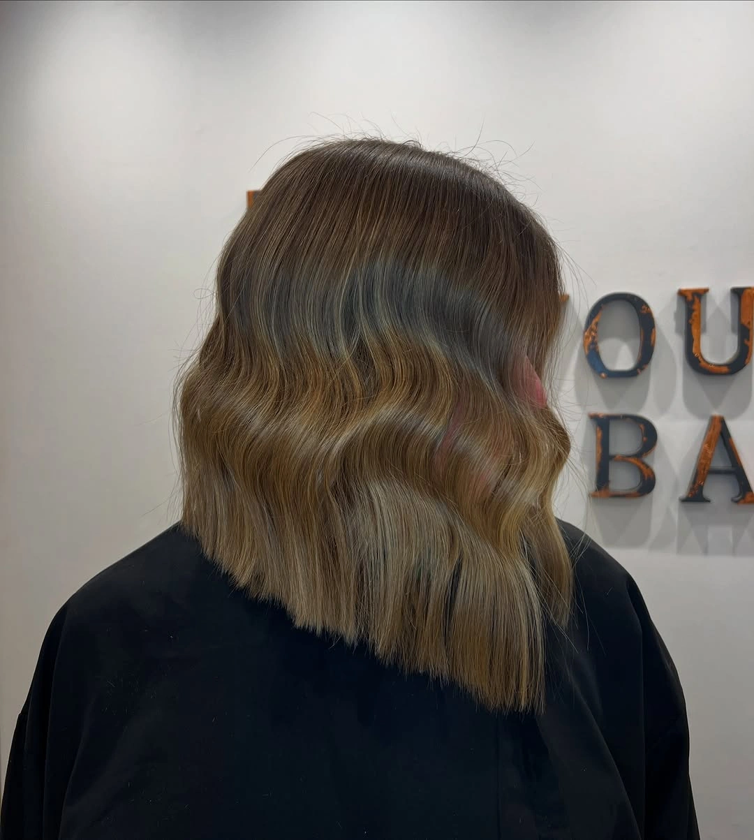 Shoulder-length wavy brown bob with warm ribbons across the back