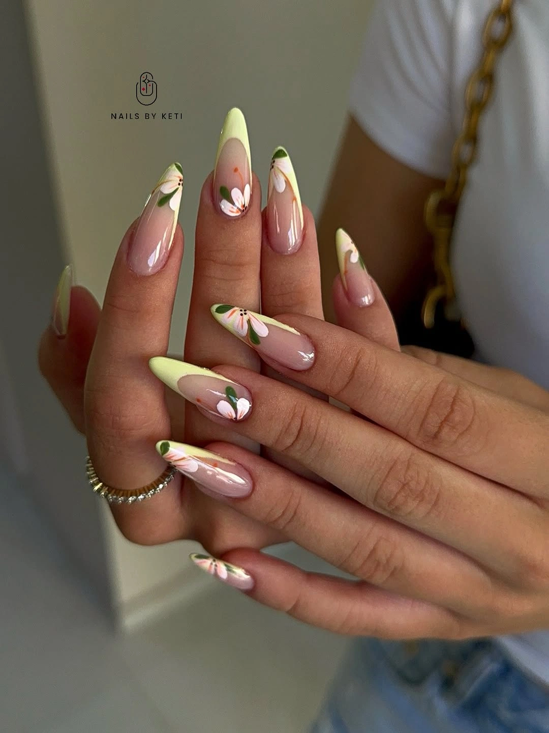 Long almond nails with pale green tips and daisy-like flowers
