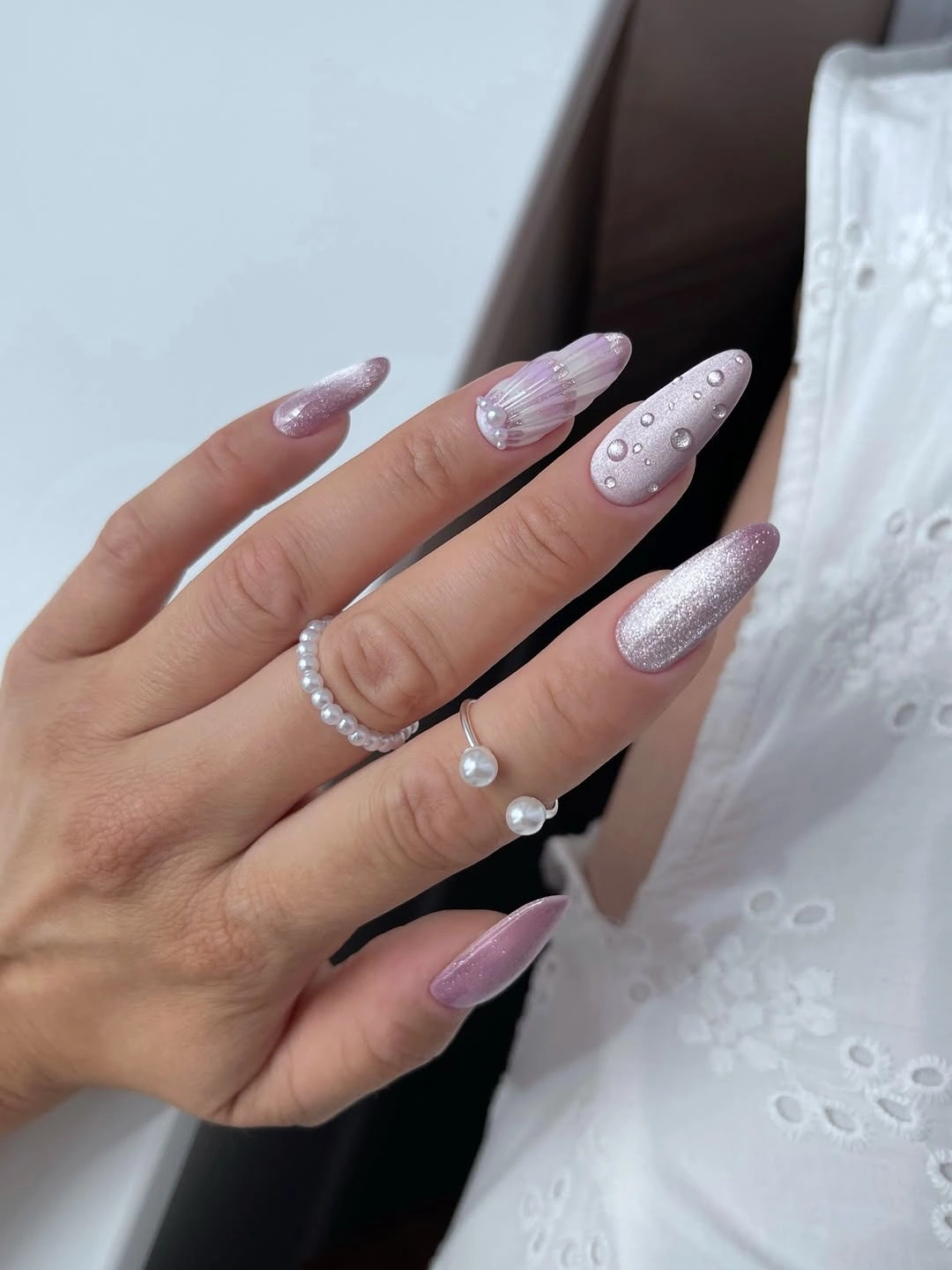 Long lilac-pink almond nails with shimmer ridges and droplet-like details
