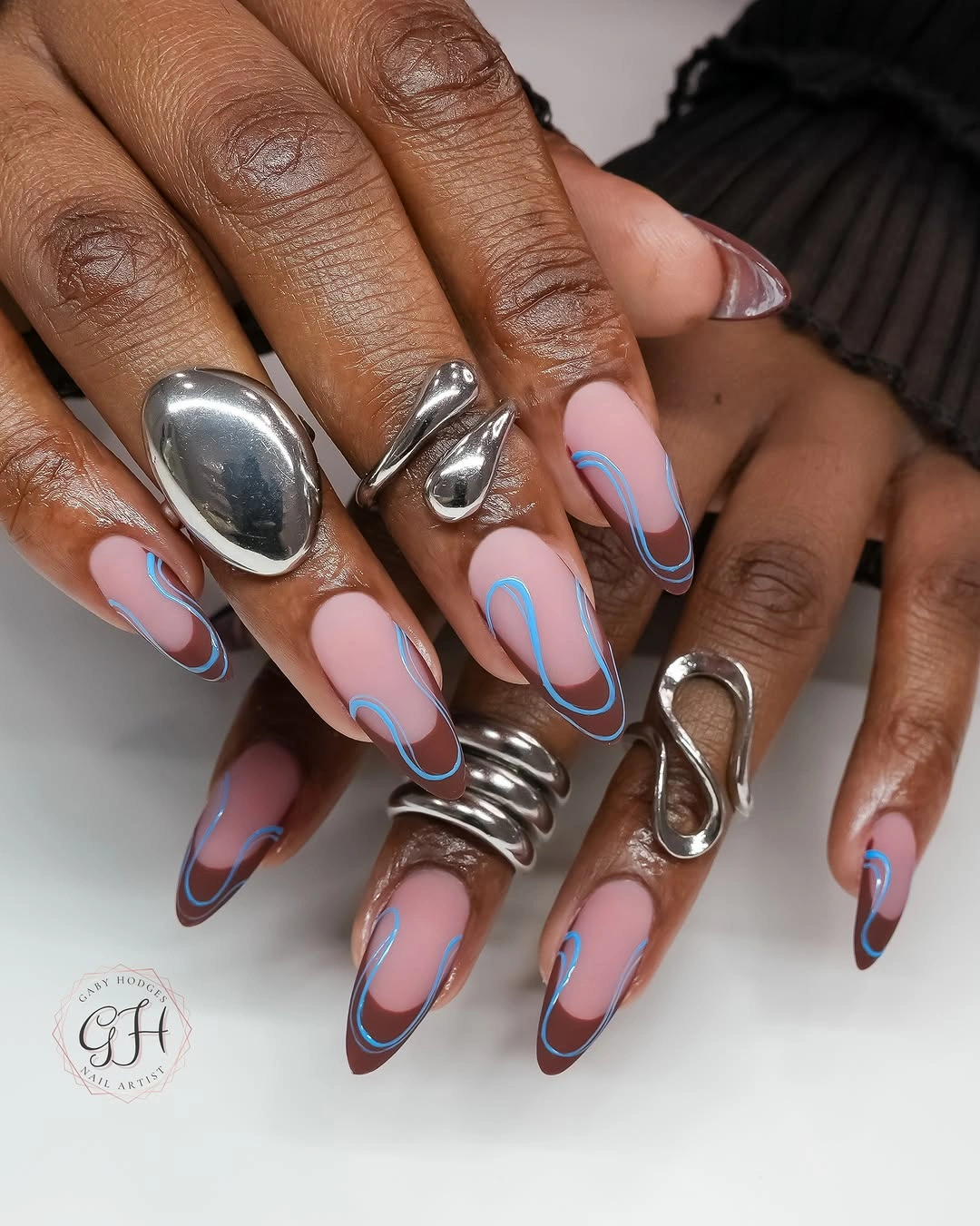 Long pink almond nails with brown and blue curved outlines