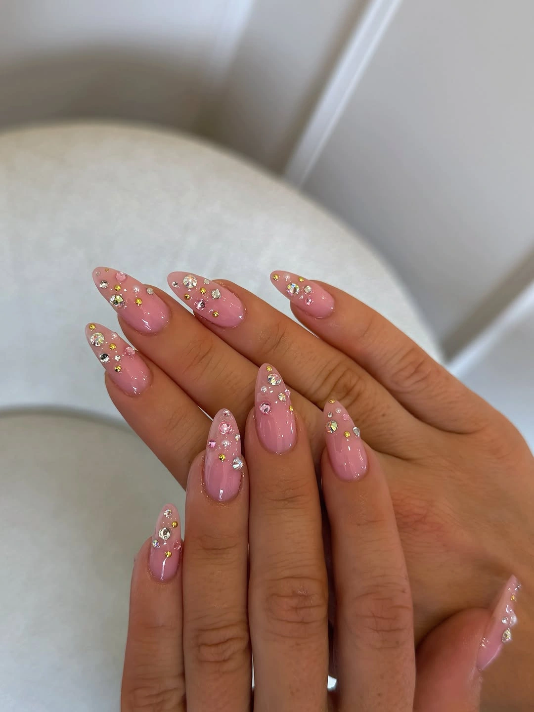 Pink almond nails with tiny reflective and flower-like details