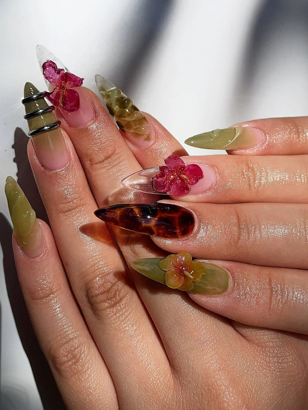 Long tapered nails with olive brown and raised-looking floral details