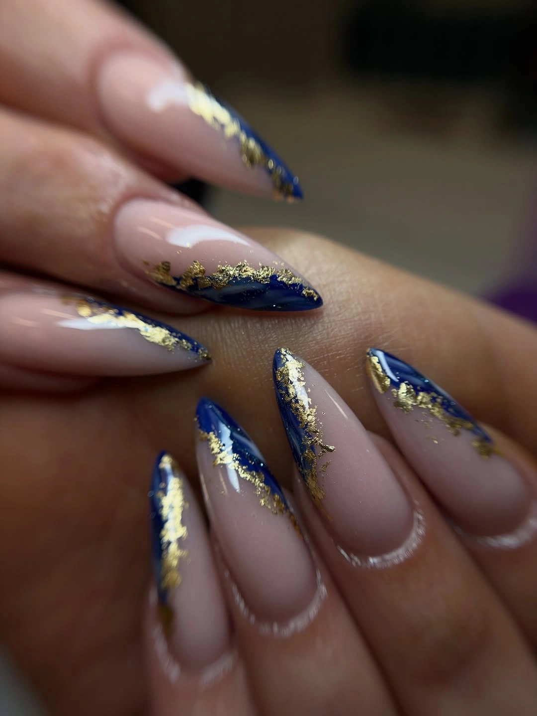 Sheer pink almond nails with blue tips and gold-colored flecks