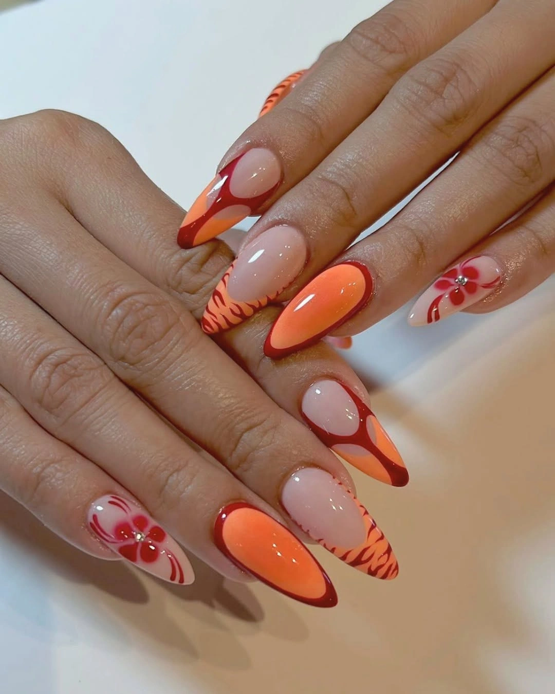 Orange and nude-pink almond nails with stripes and flower-like details