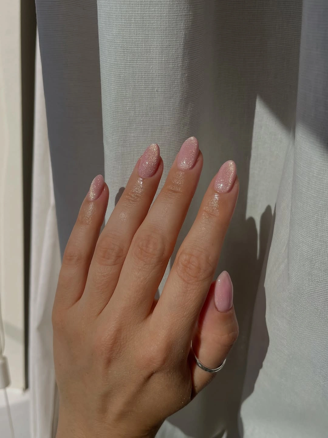 Pale pink almond nails with fine reflective sparkle