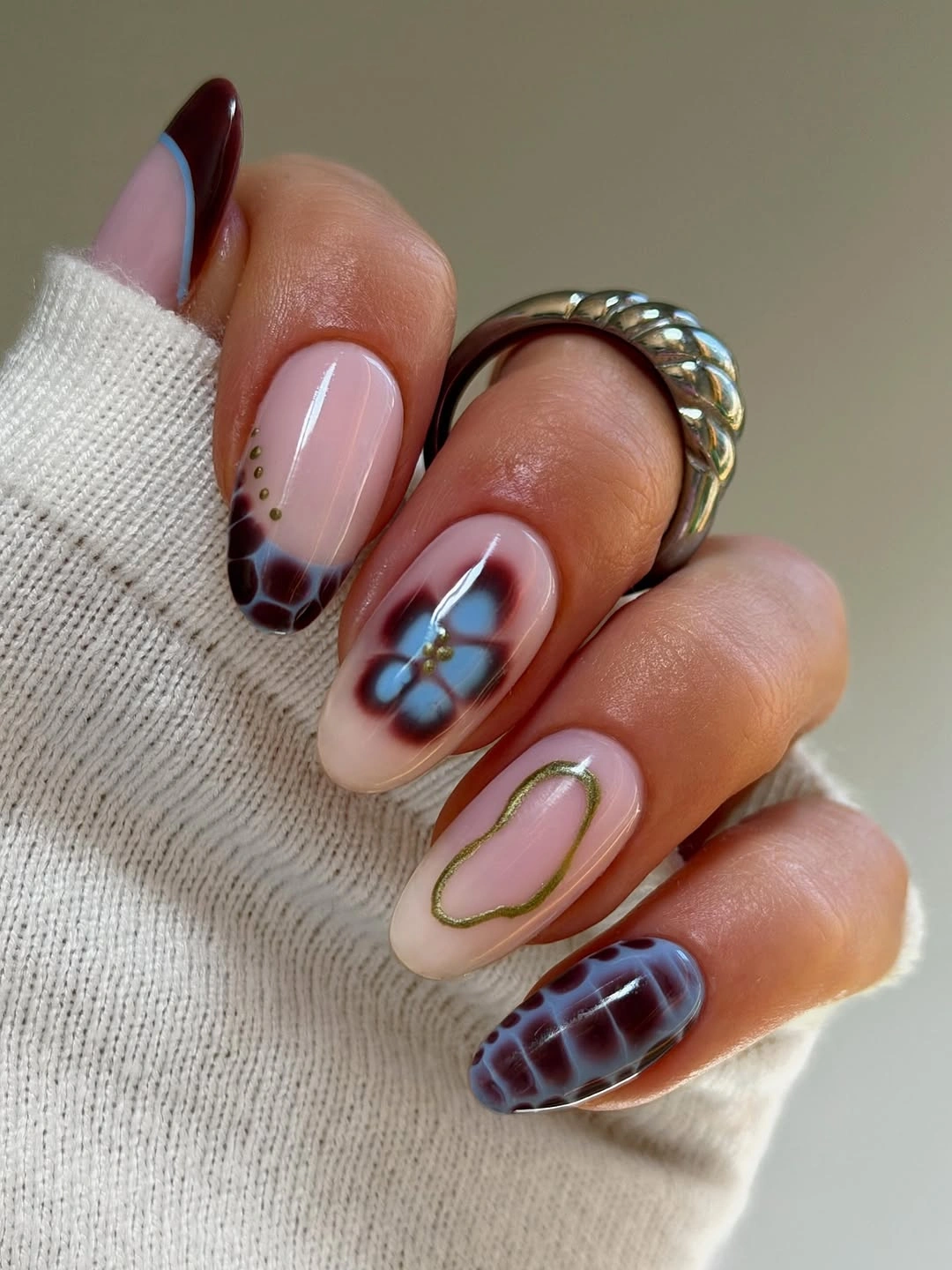 Sheer pink almond nails with brown blue and gold-colored details