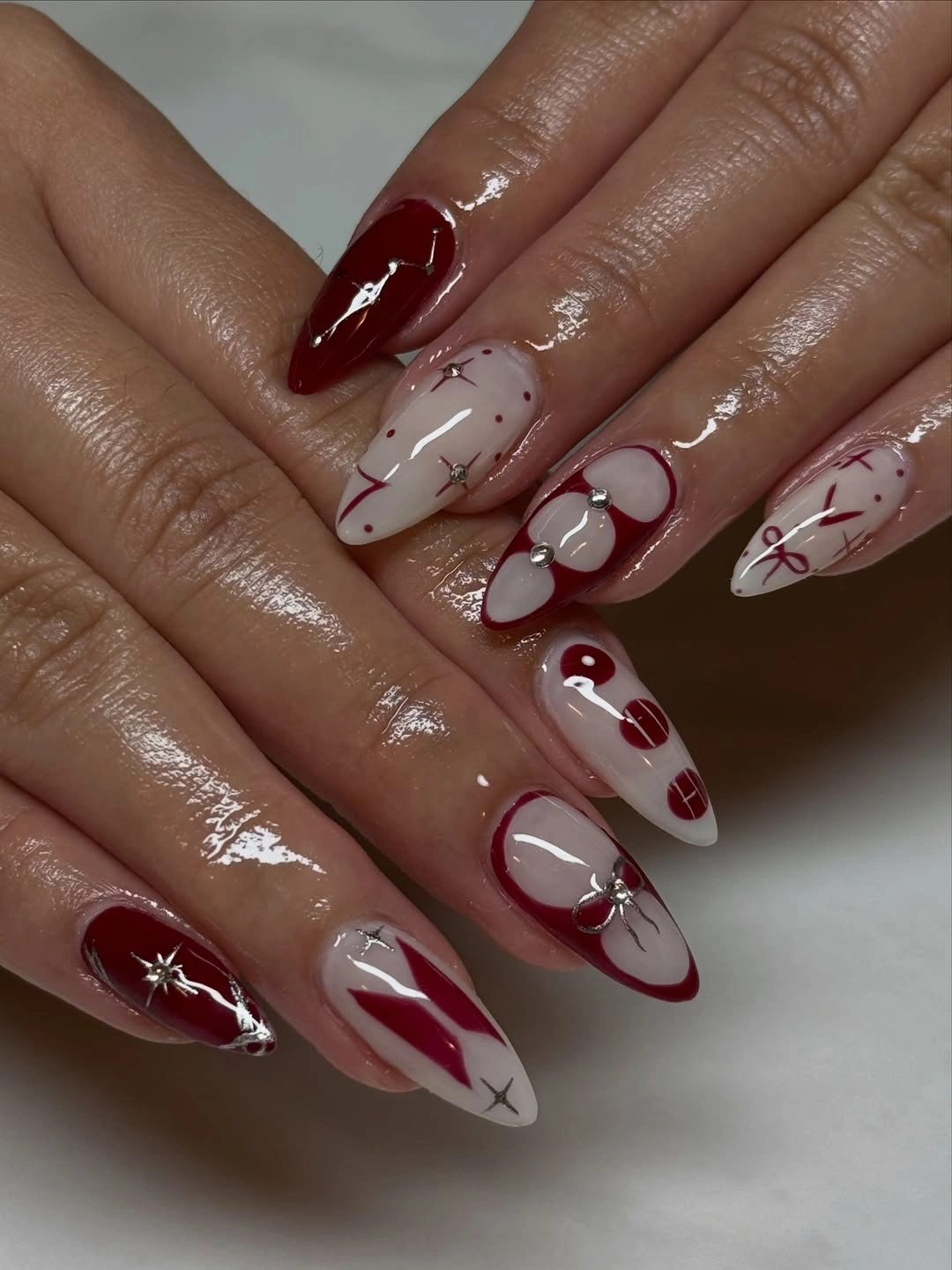 Burgundy and ivory almond nails with loops dots and stars
