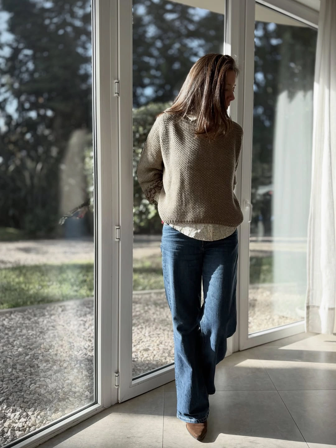 Taupe knit sweater with medium-blue straight jeans indoors
