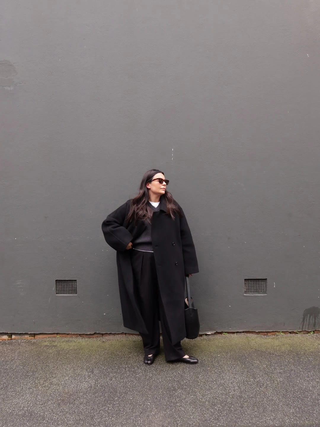 Long black coat with wide black trousers and sunglasses