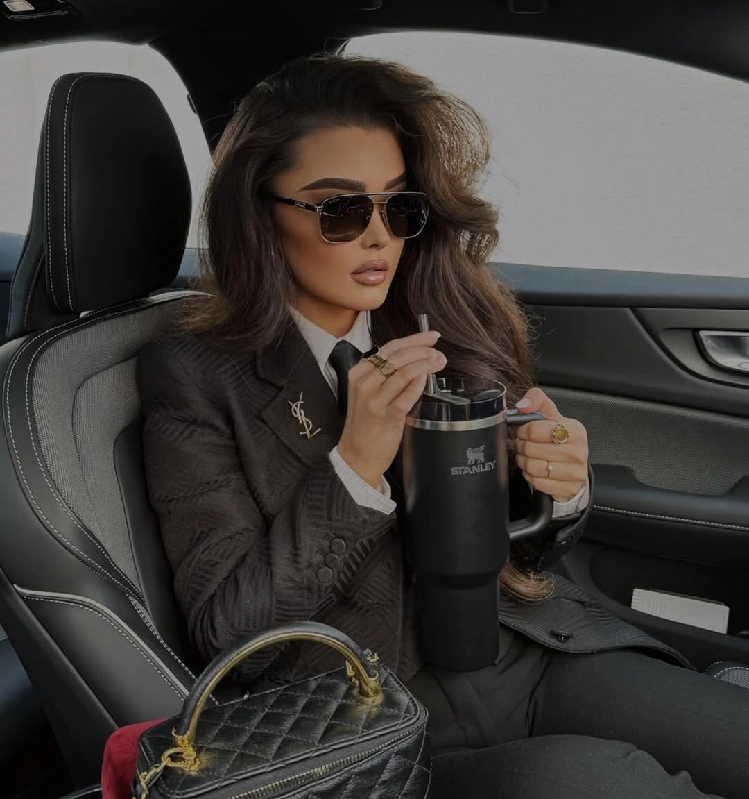 Dark brown blazer with black trousers sunglasses and small bag
