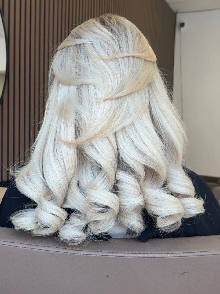 Medium-length very pale blonde hair with swept upper sections and curled ends
