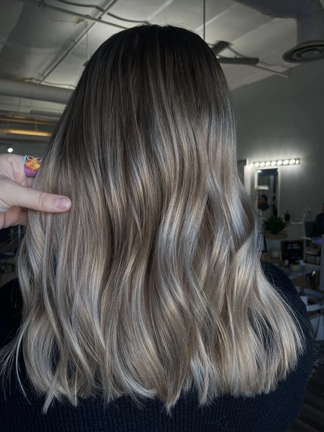 Below-shoulder cool blonde waves with dark roots and pale ends