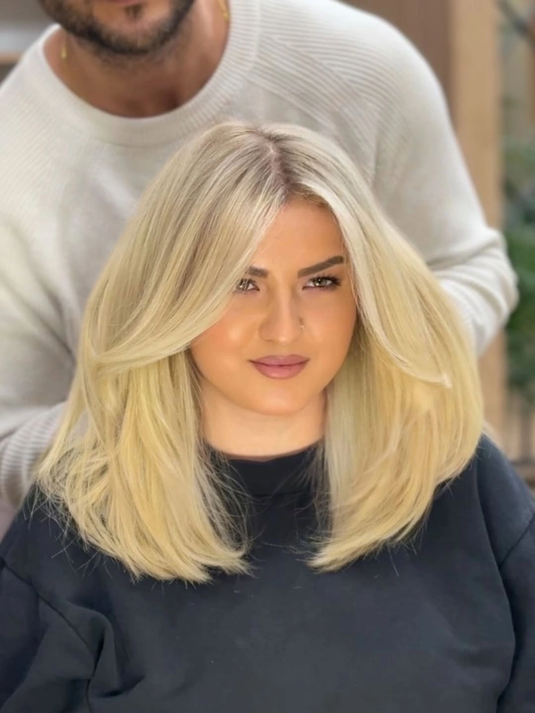 Shoulder-length pale blonde long bob with side-swept front and rounded ends
