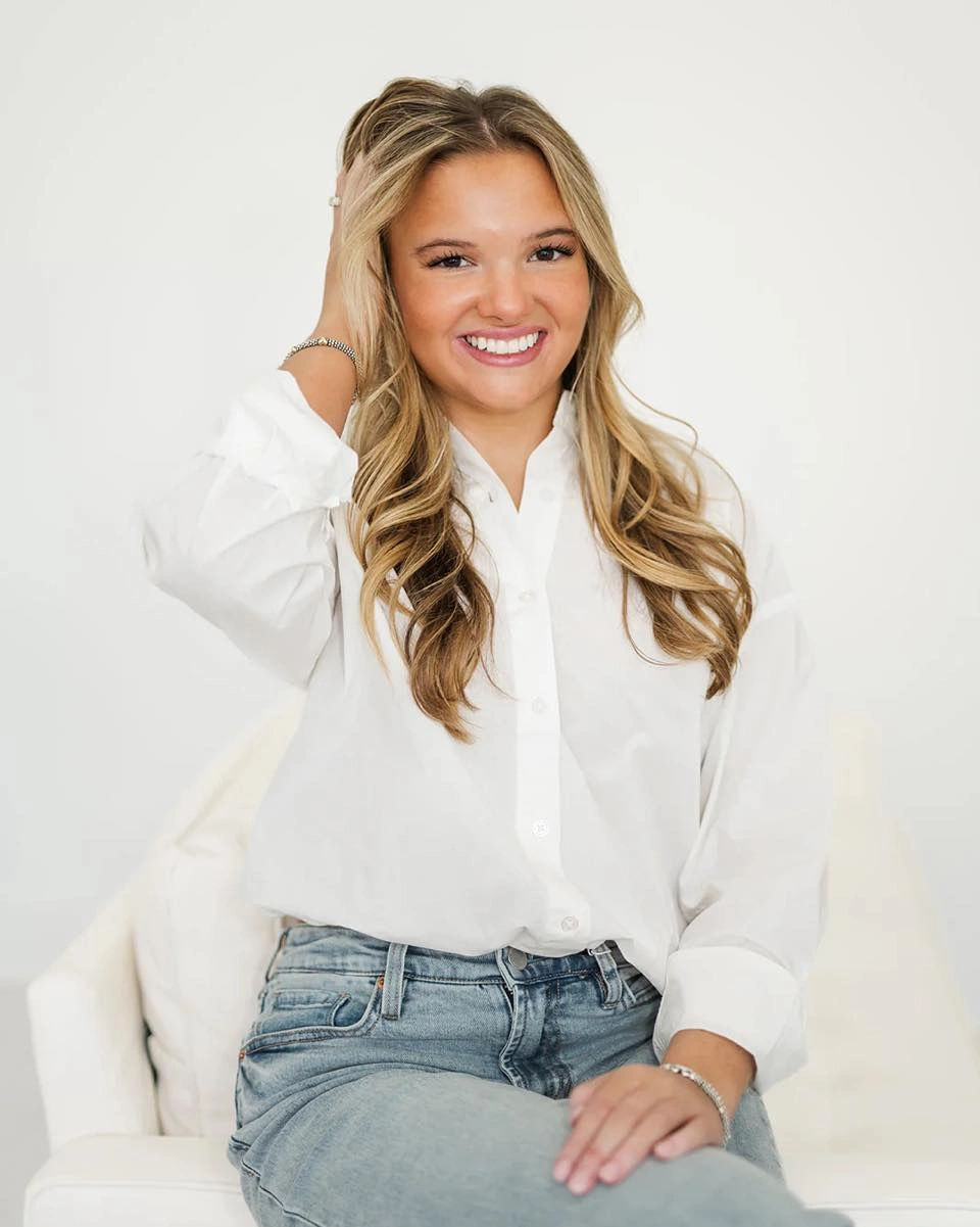 White button-up shirt light blue jeans and seated portrait