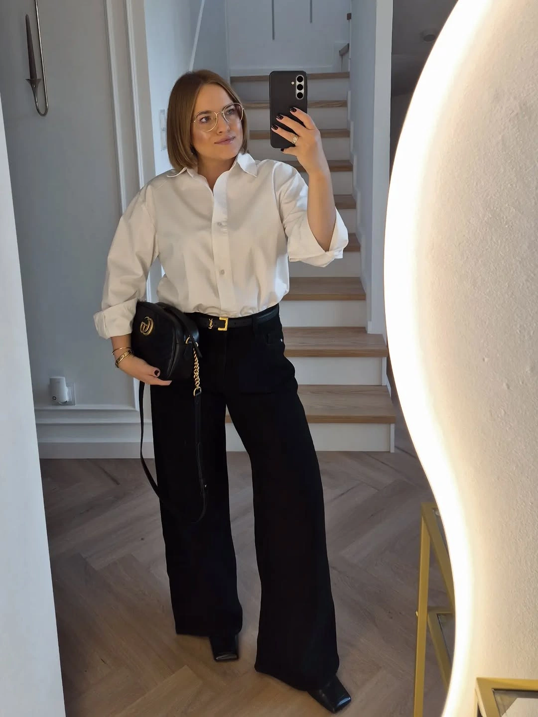 White button-up tucked into wide black trousers with black handbag