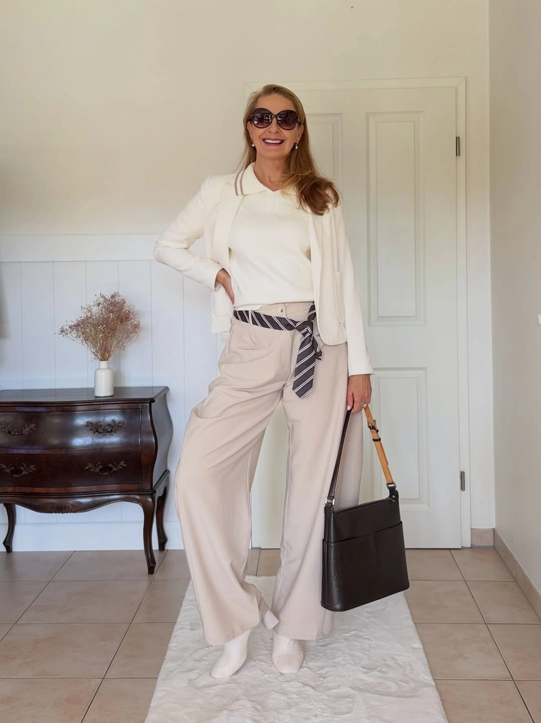 Cream cardigan white blouse beige trousers striped accent black handbag