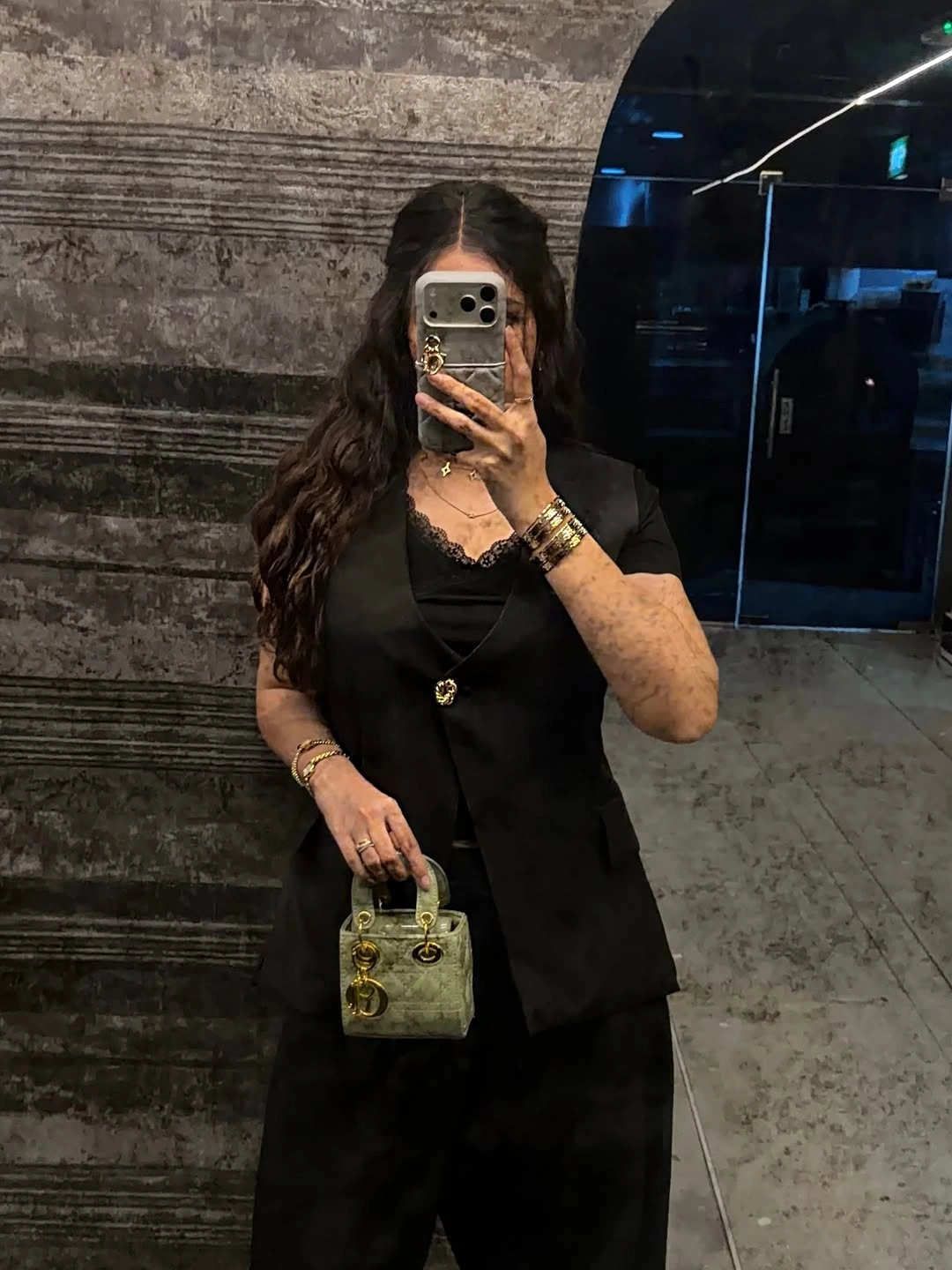 Black sleeveless layer over light blouse with wide dark trousers