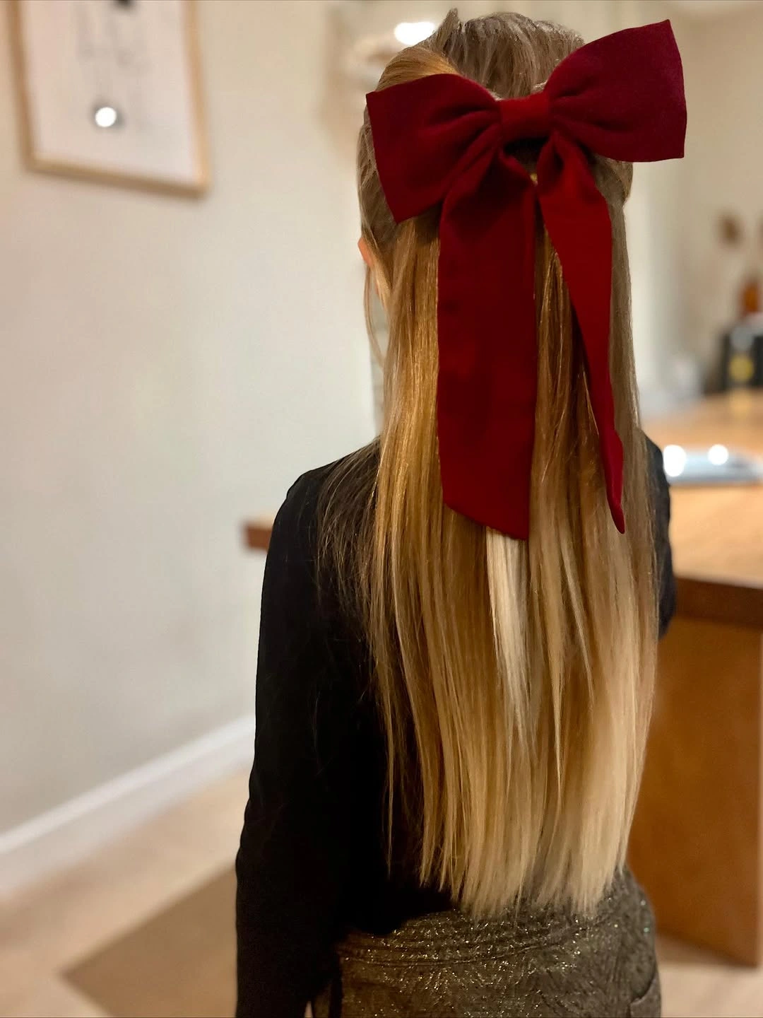 Straight blonde hair gathered beneath oversized deep red bow